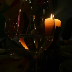 white wine in wine glass near lighted yellow pillar candles
