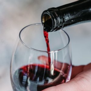 person pouring wine on clear wine glass